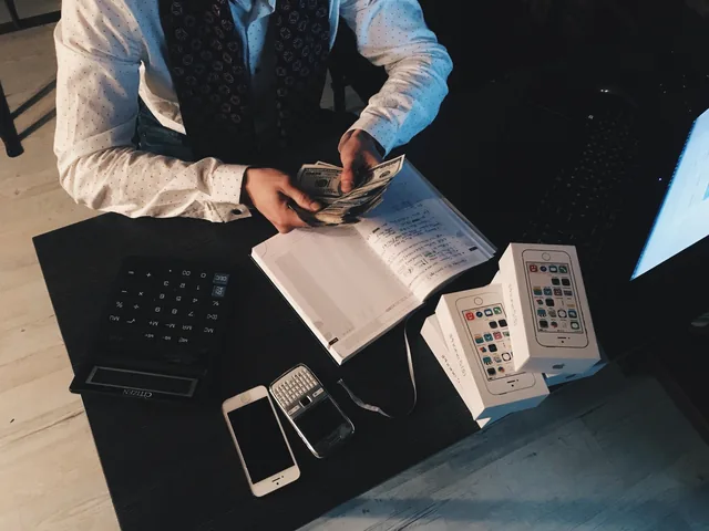 Profissional a organizar valores e informação financeira junto a dispositivos de trabalho, representando processos administrativos recorrentes