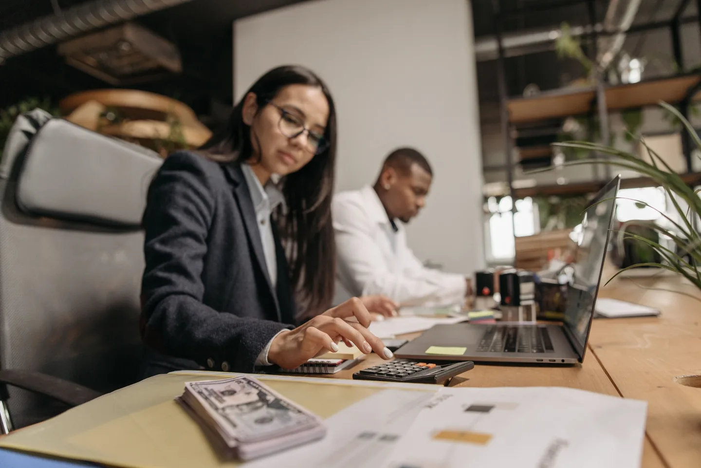 Profissional de contabilidade a trabalhar com calculadora e computador, representando organização, proximidade e processos digitais mais simples